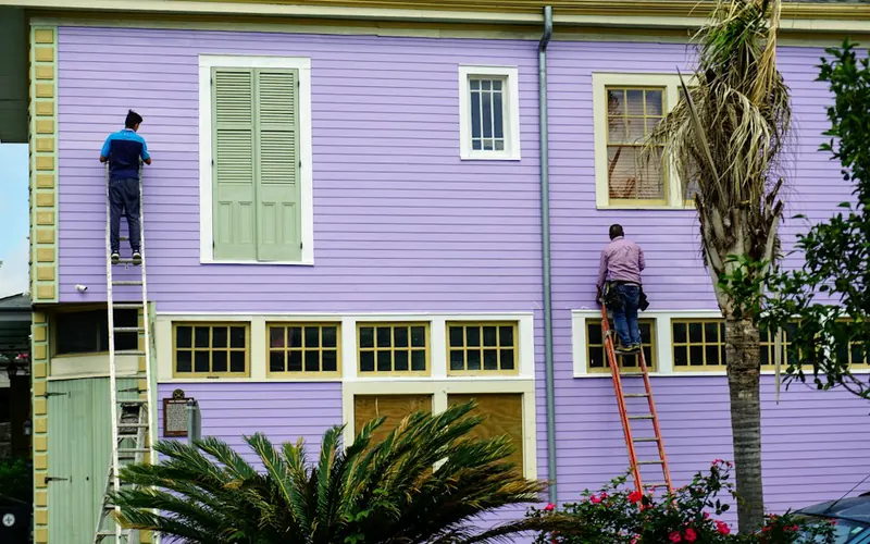 Painters on ladders painting the outside of a house