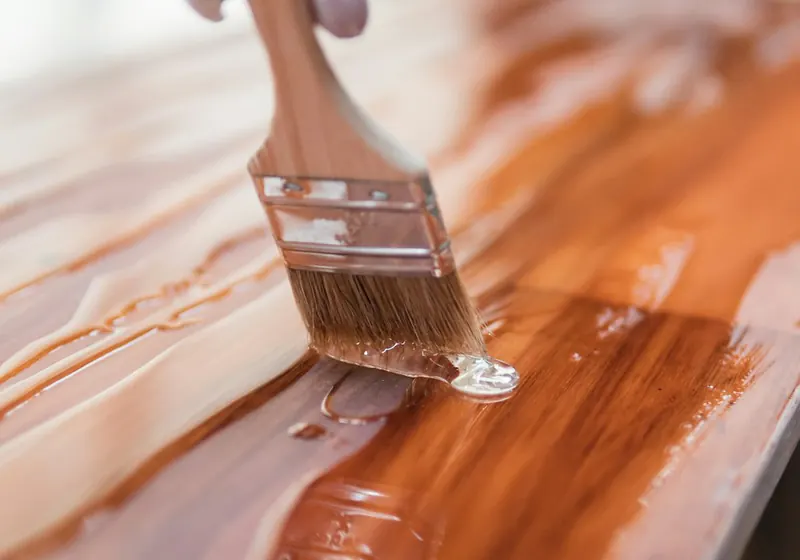 Brush applying glossy varnish to a wooden table